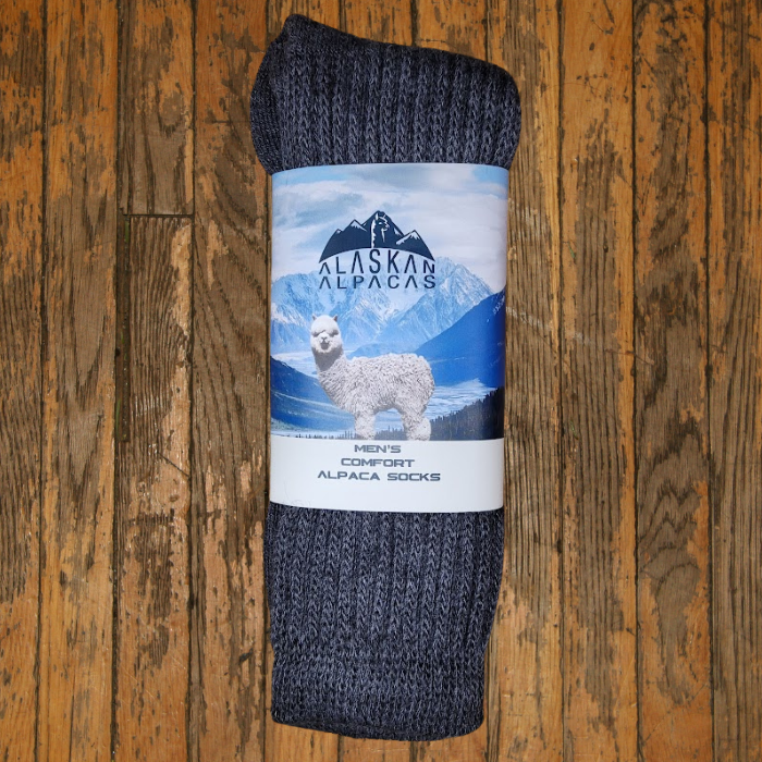 Dark gray alpaca socks rolled up, wrapped with a label depicting an alpaca and mountains.