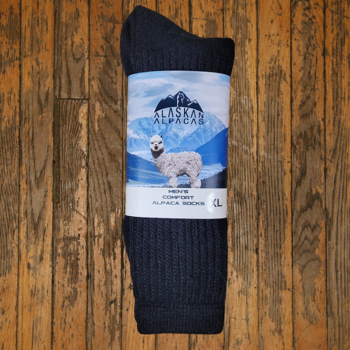Dark gray alpaca socks with label showing an alpaca and mountains, on wooden surface.
