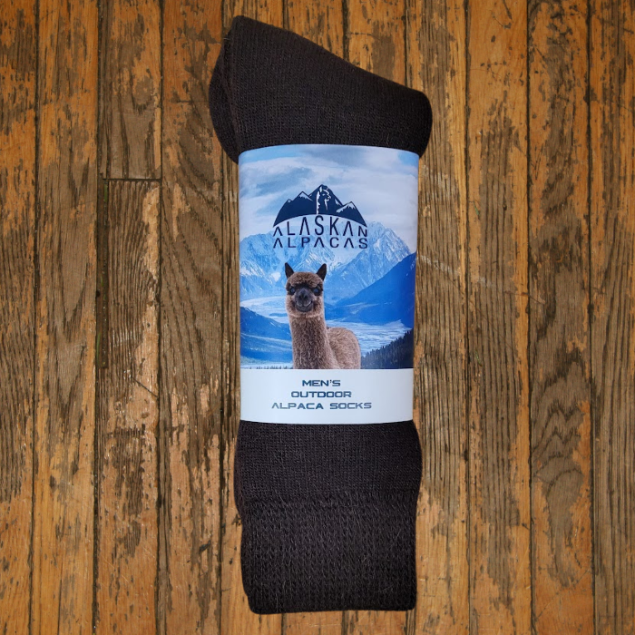 Brown alpaca socks with a label featuring an alpaca and Alaskan mountain scene.