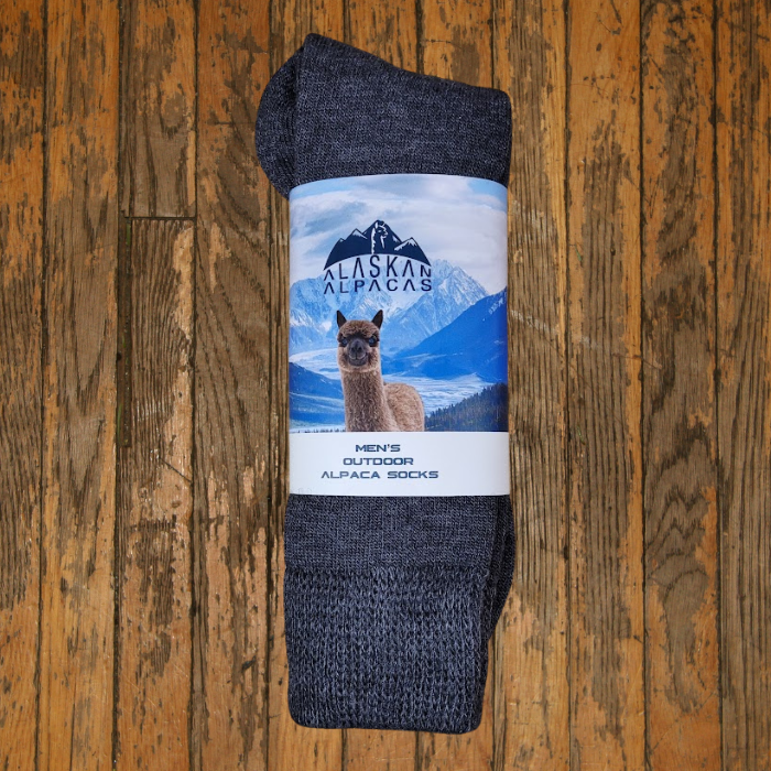 A pair of dark gray alpaca socks with a label showing an alpaca and snowy mountain.
