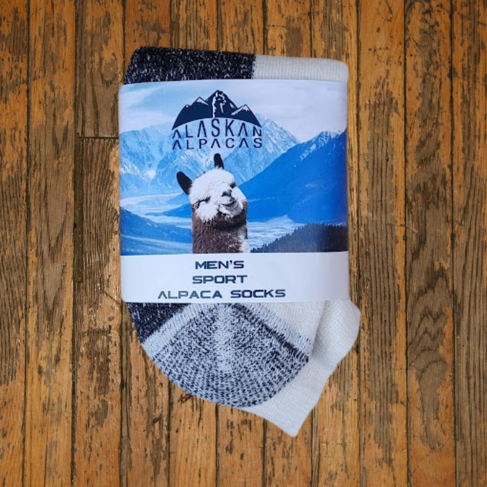 Pair of alpaca socks with packaging on a wood surface.