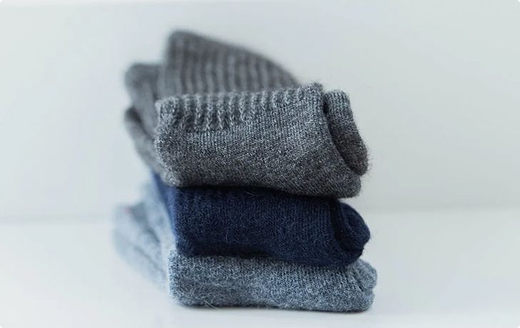 Stack of folded gray and navy socks against a white background.