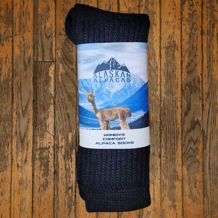 Dark gray alpaca socks with a product label featuring an alpaca and mountains on a wood background.