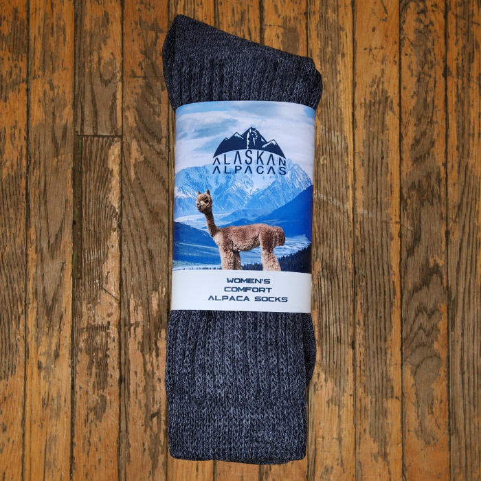 Pair of gray Alaskan Alpaca socks with packaging featuring an alpaca and mountain scene.