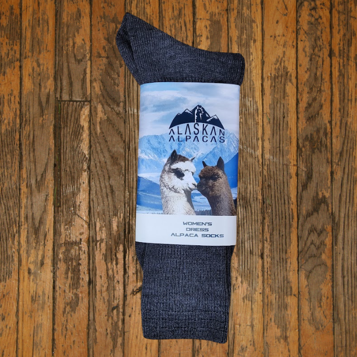 Gray alpaca socks with a label featuring two alpaca images against a snowy mountain backdrop.