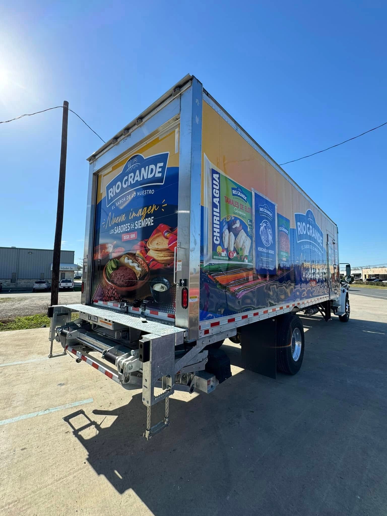 A food truck parked outdoors with colorful graphics advertising burgers and fries on its side panels.