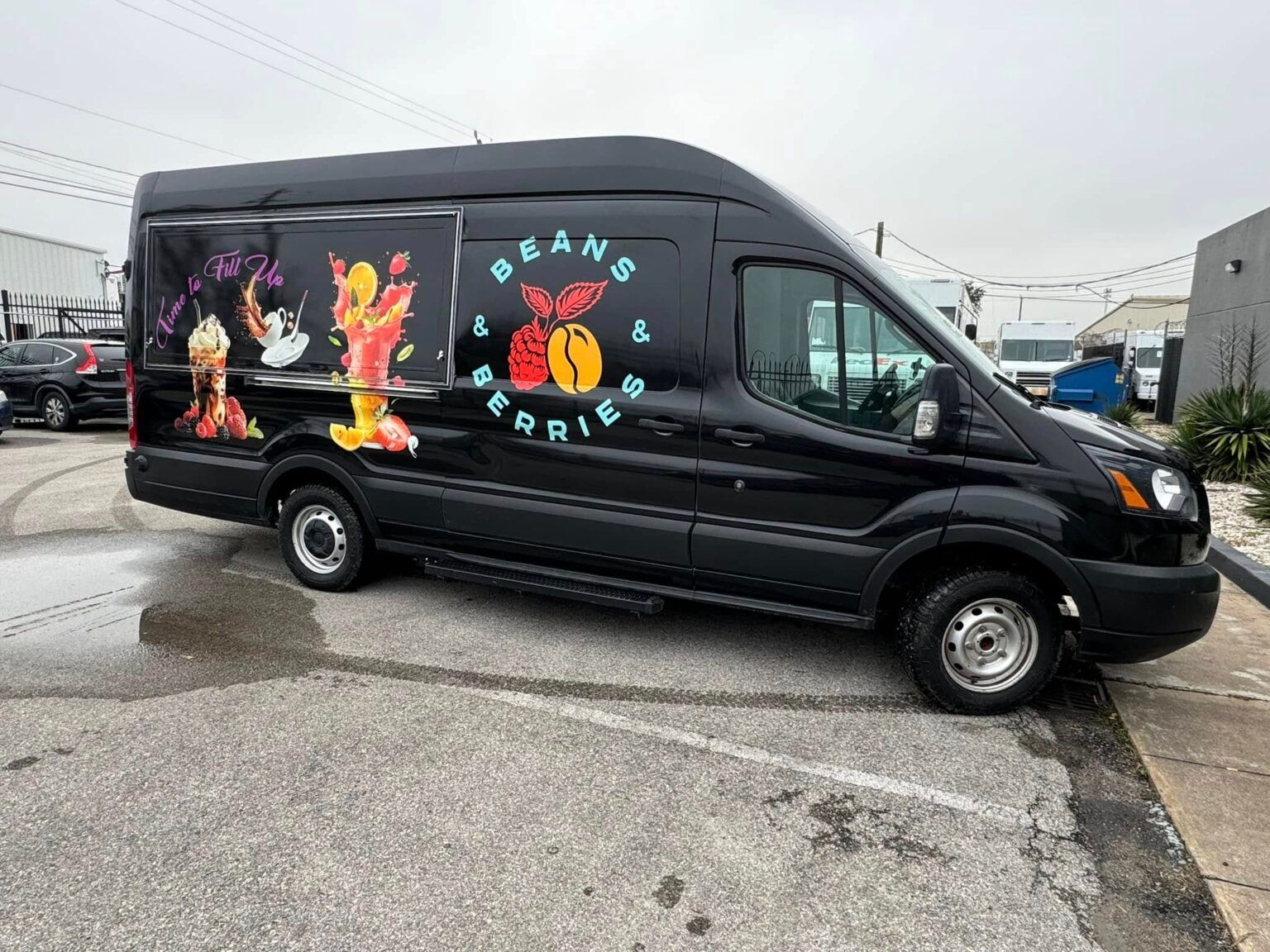 A row of branded company vans parked outside the South Houston Sign and Print Shop building.