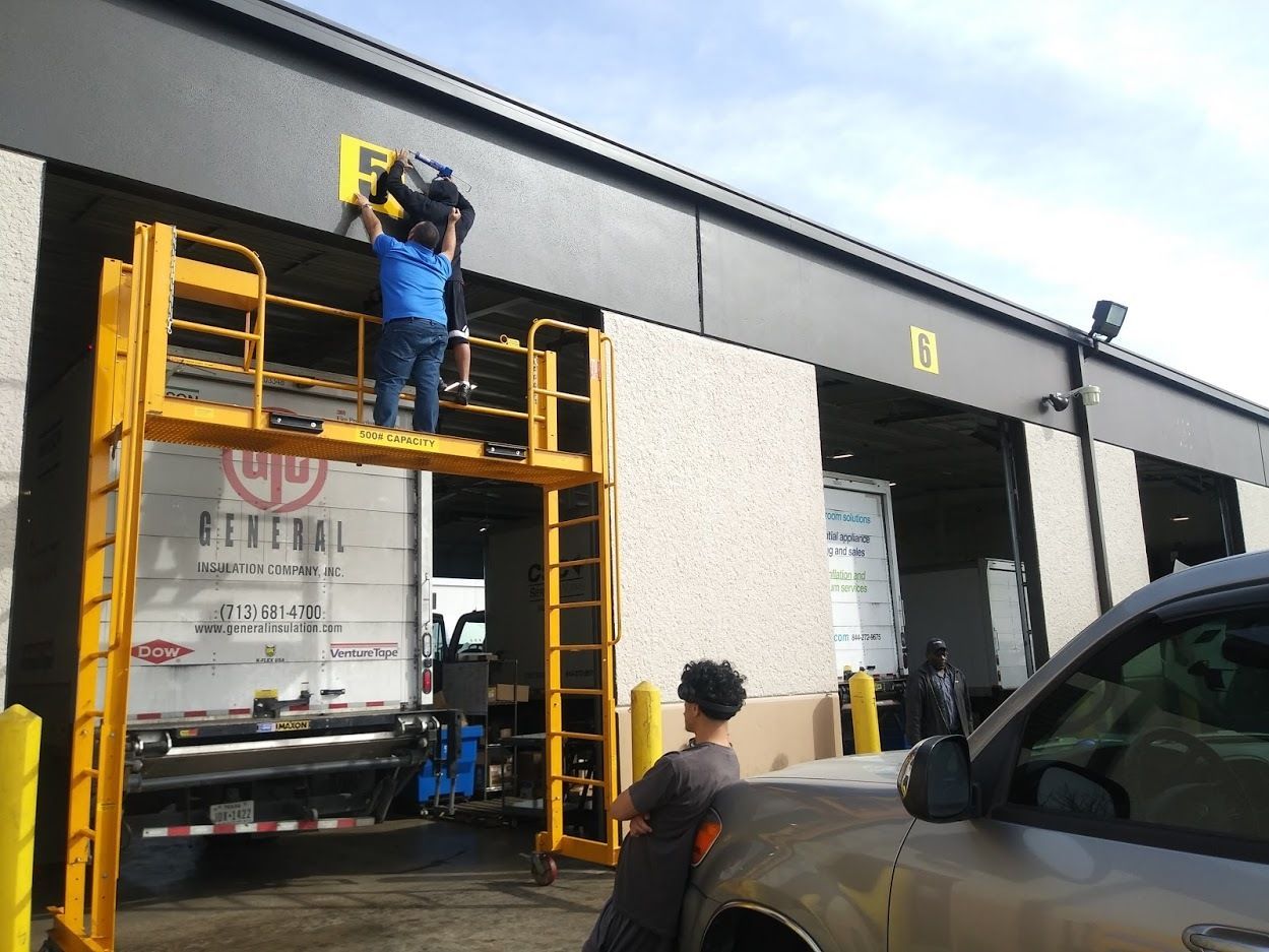 Three people in matching uniforms apply a large red and white 
