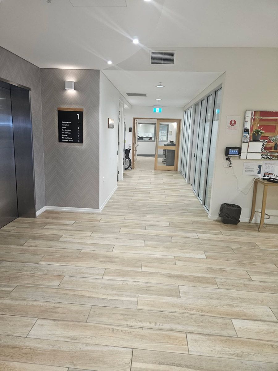 A Long Hallway With a Wooden Floor and a Elevator — Nick Favot Painting In Bohle, QLD