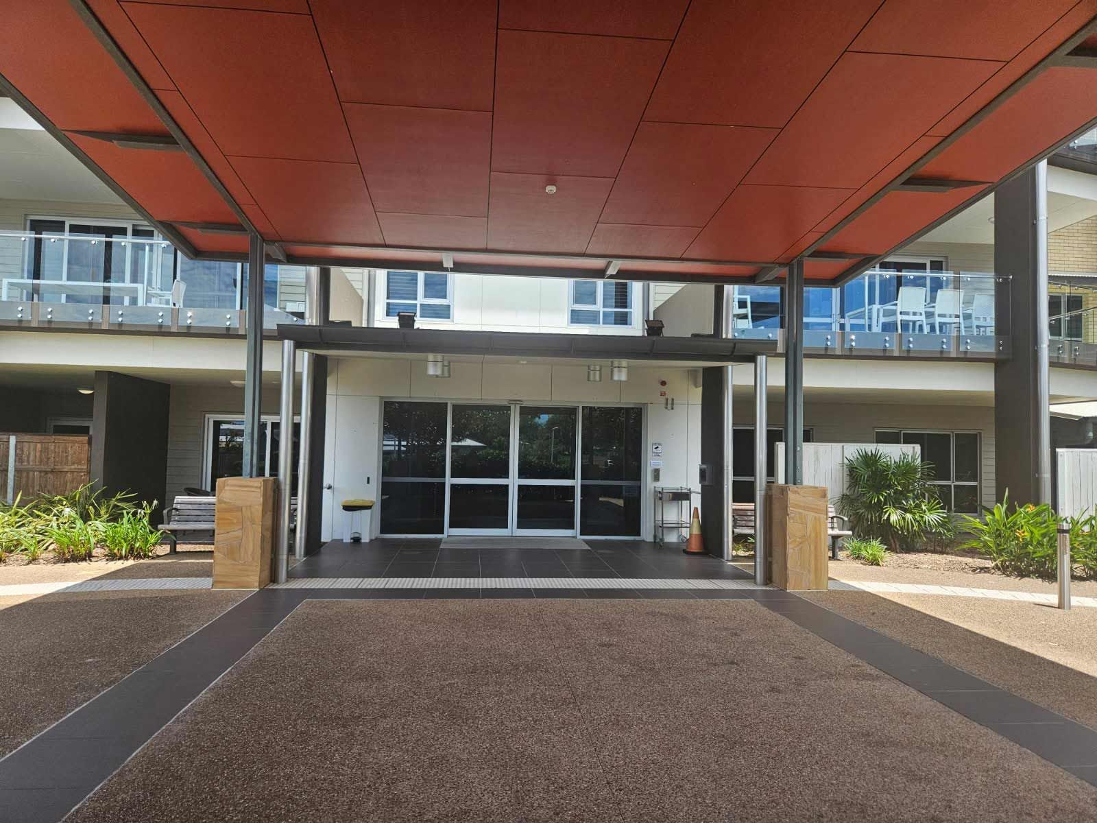 Building Entrance With a Red Overhang and Large Glass Doors — Nick Favot Painting In Bohle, QLD