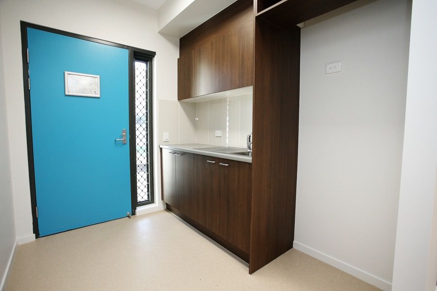 A Kitchen With a Blue Door and Wooden Cabinets — Nick Favot Painting in Bohle, QLD