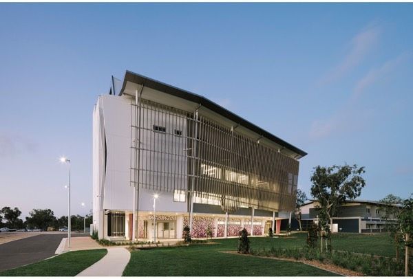 A Large White Building With a Lot of Windows is Sitting on Top of a Lush Green Field — Nick Favot Painting in Bohle, QLD
