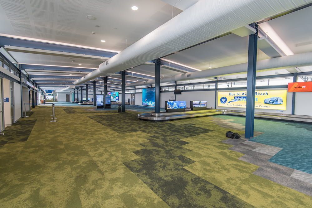 A Large Empty Airport Terminal With Green Carpet and a Conveyor Belt — Nick Favot Painting in Bohle, QLD