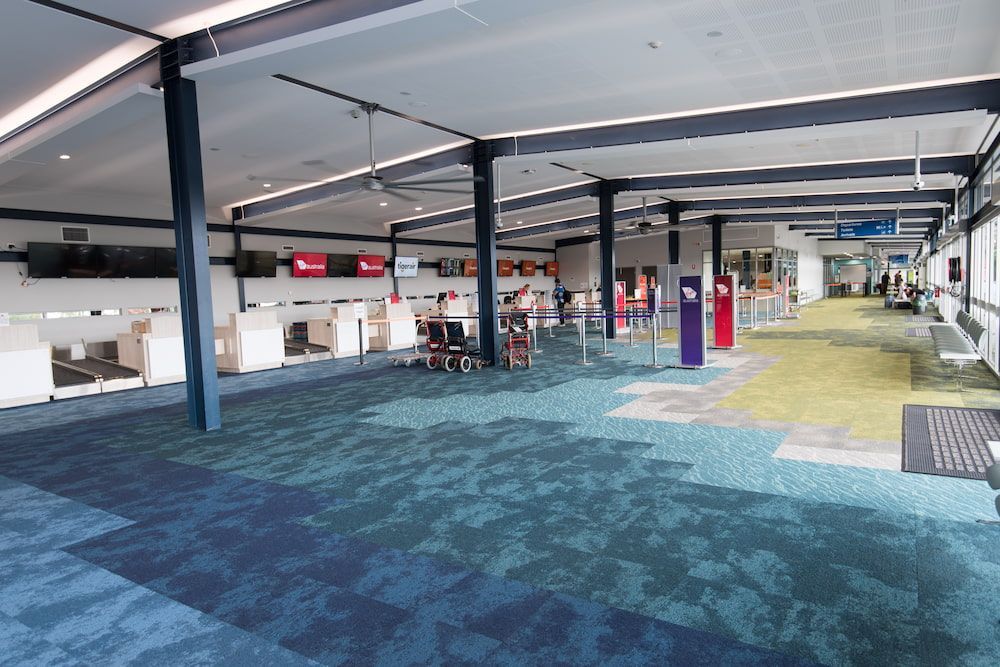 A Large Empty Room With a Blue Carpet and White Walls — Nick Favot Painting in Bohle, QLD