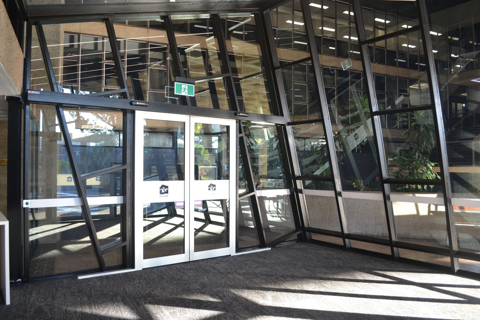 A Modern Building Entrance With Glass Walls and Double Doors — Nick Favot Painting In Bohle, QLD