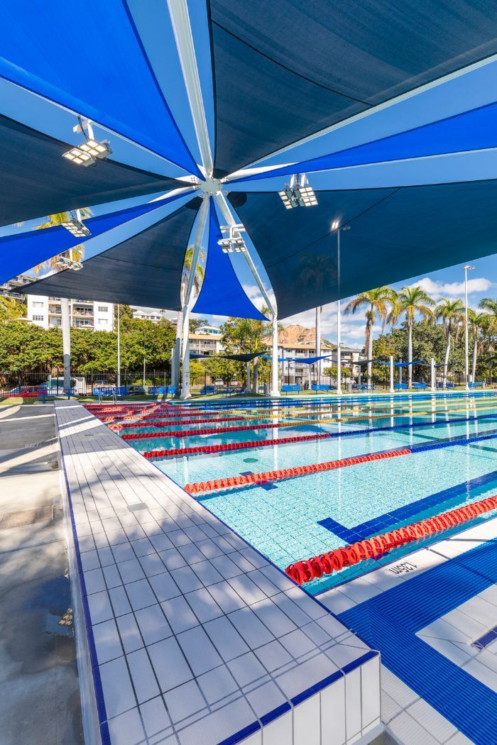 A Large Swimming Pool With Blue and White Umbrellas Over It — Nick Favot Painting in Bohle, QLD