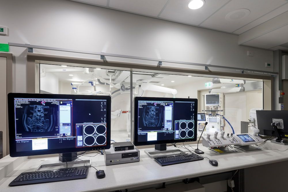 Two Computer Monitors Are Sitting on a Desk in a Hospital Room — Nick Favot Painting in Bohle, QLD