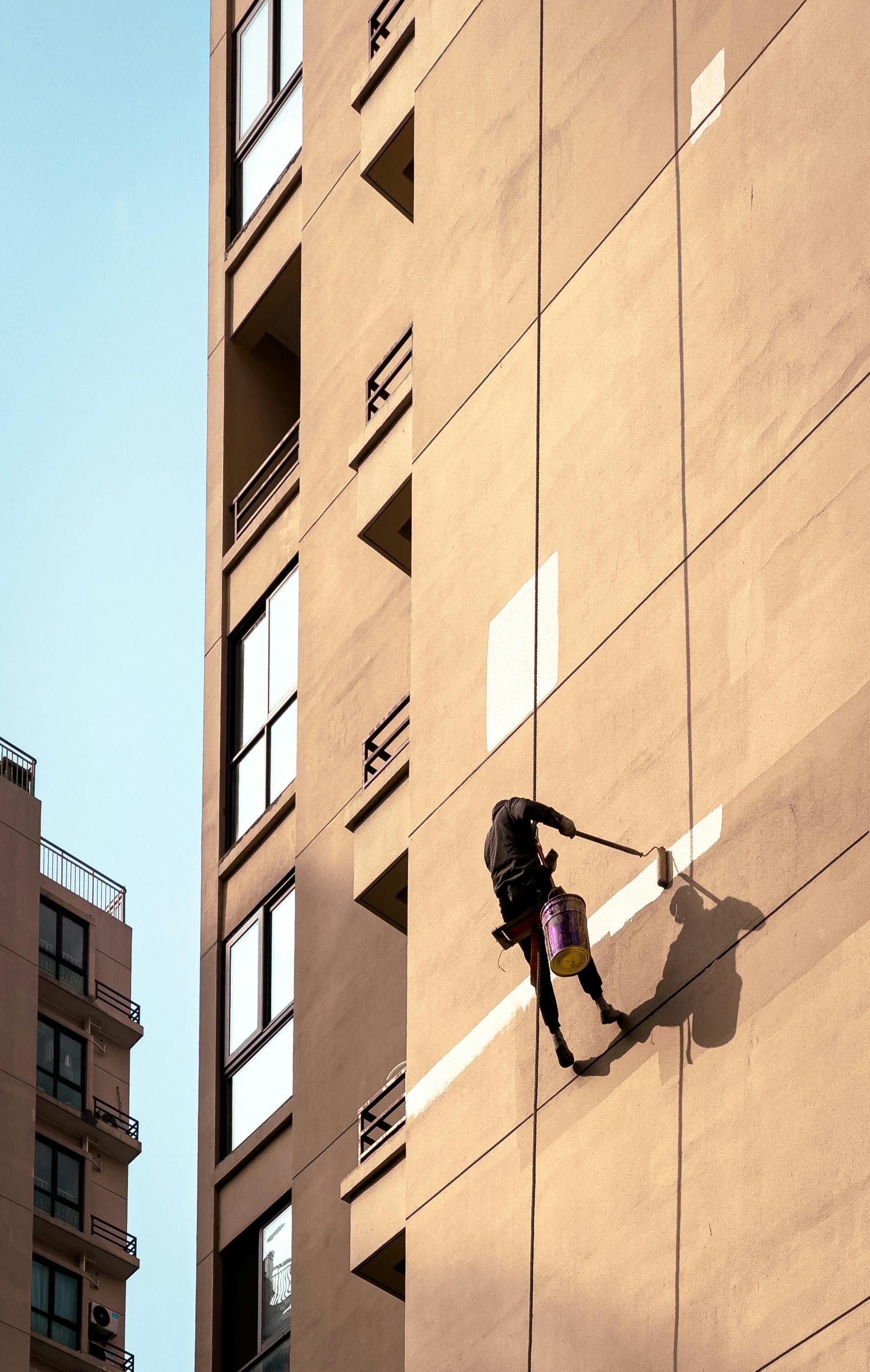 A person is climbing up the side of a tall building — Nick Favot Painting in Bohle, QLD
