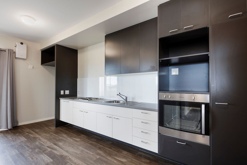 A Kitchen With Black and White Cabinets and a Stainless Steel Oven — Nick Favot Painting in Bohle, QLD