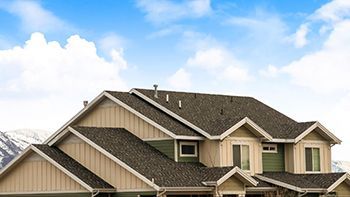 A large house with a roof and a blue sky in the background.