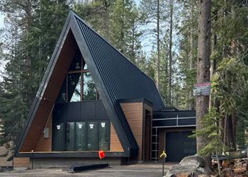 A modern a frame house in the middle of a forest.