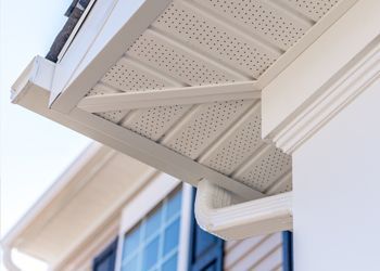 A close up of a white soffit and gutter on a house.