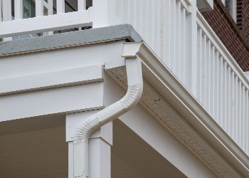 A close up of a white gutter on the side of a house.