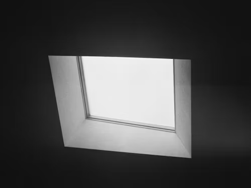 Skylight in a dark room, framed with angled, light-colored walls; bright natural light is visible through the window.