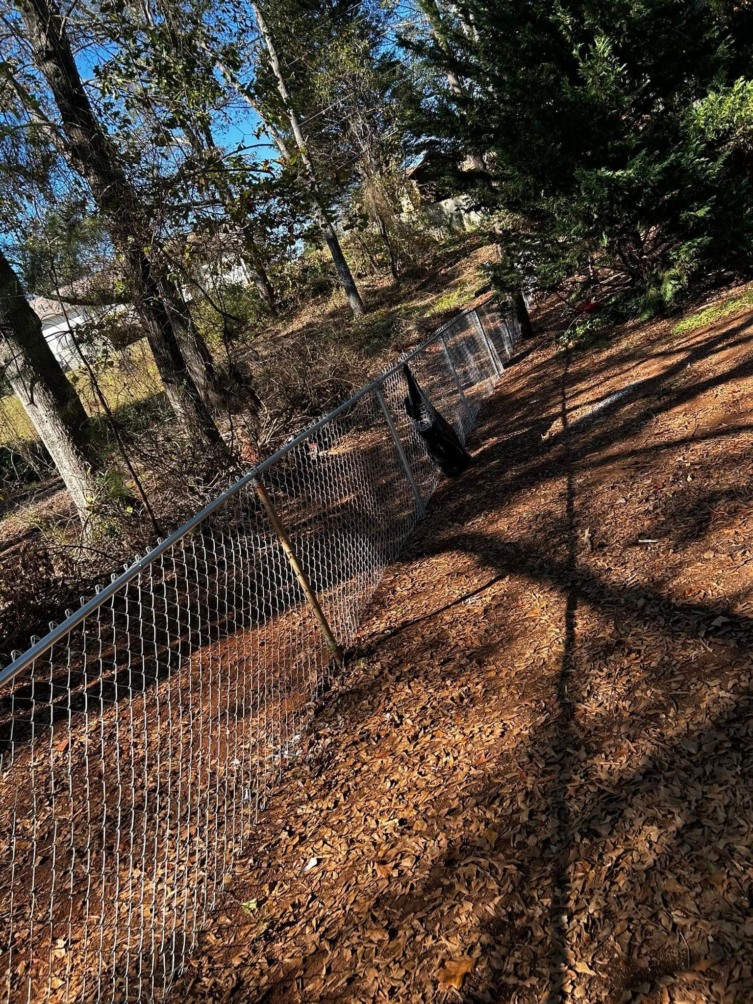 Water streams from an outdoor sprinkler. Brown leaves cover the ground with trees in the background.