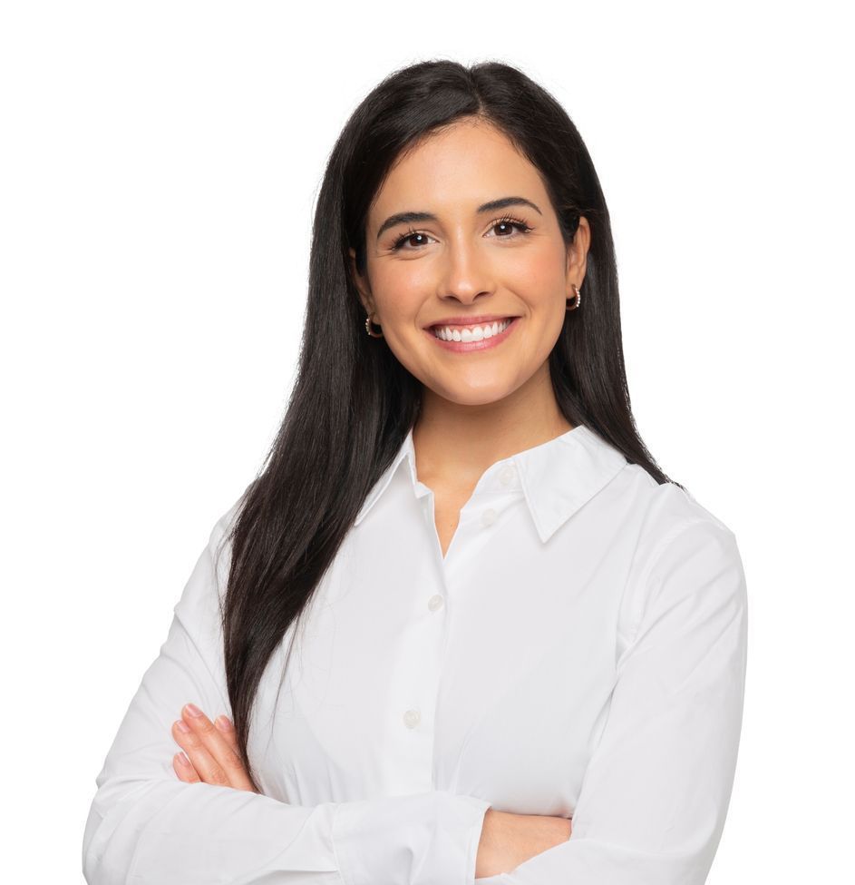A woman in a white shirt is smiling with her arms crossed.