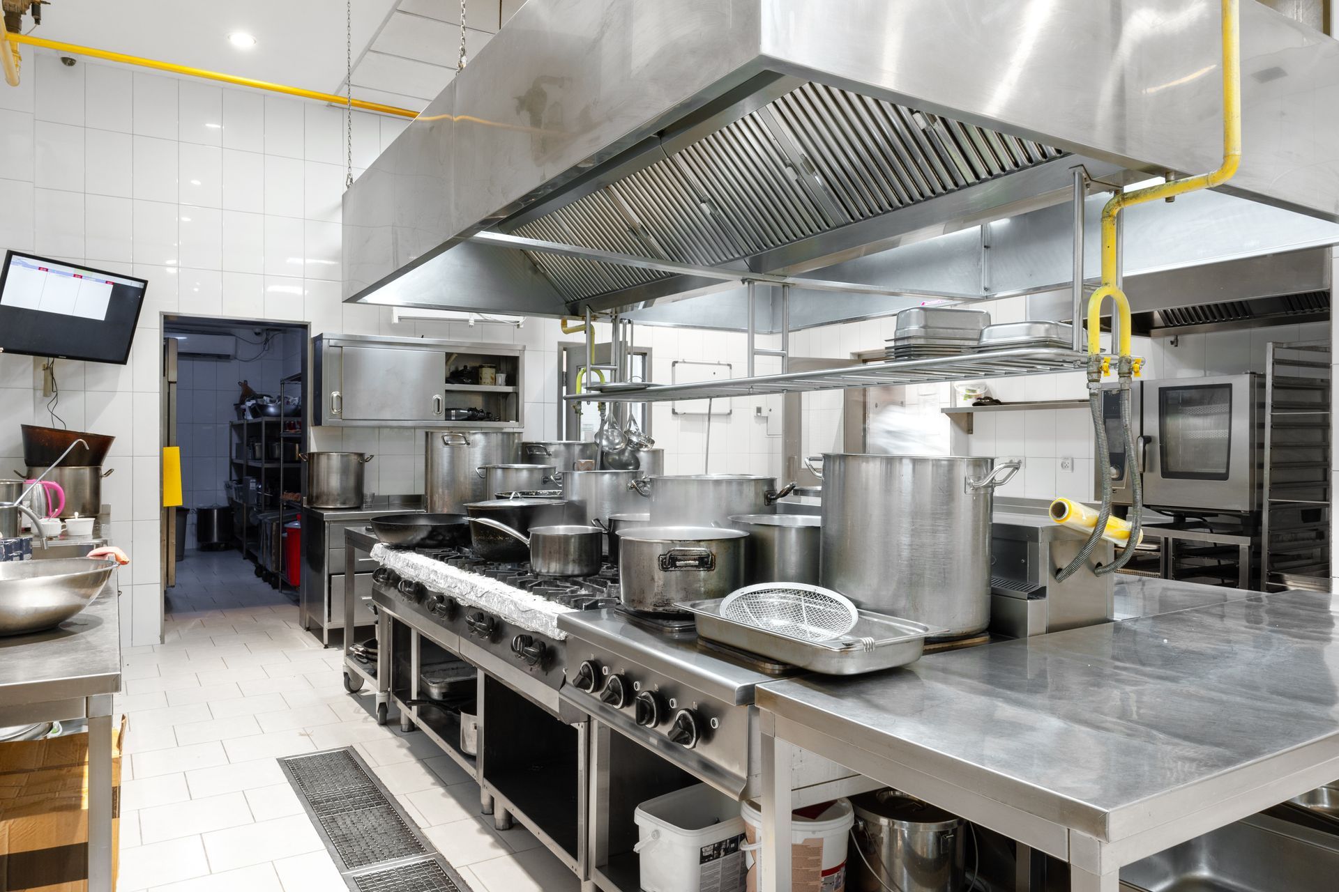 A large commercial kitchen with many pots and pans on the stove.