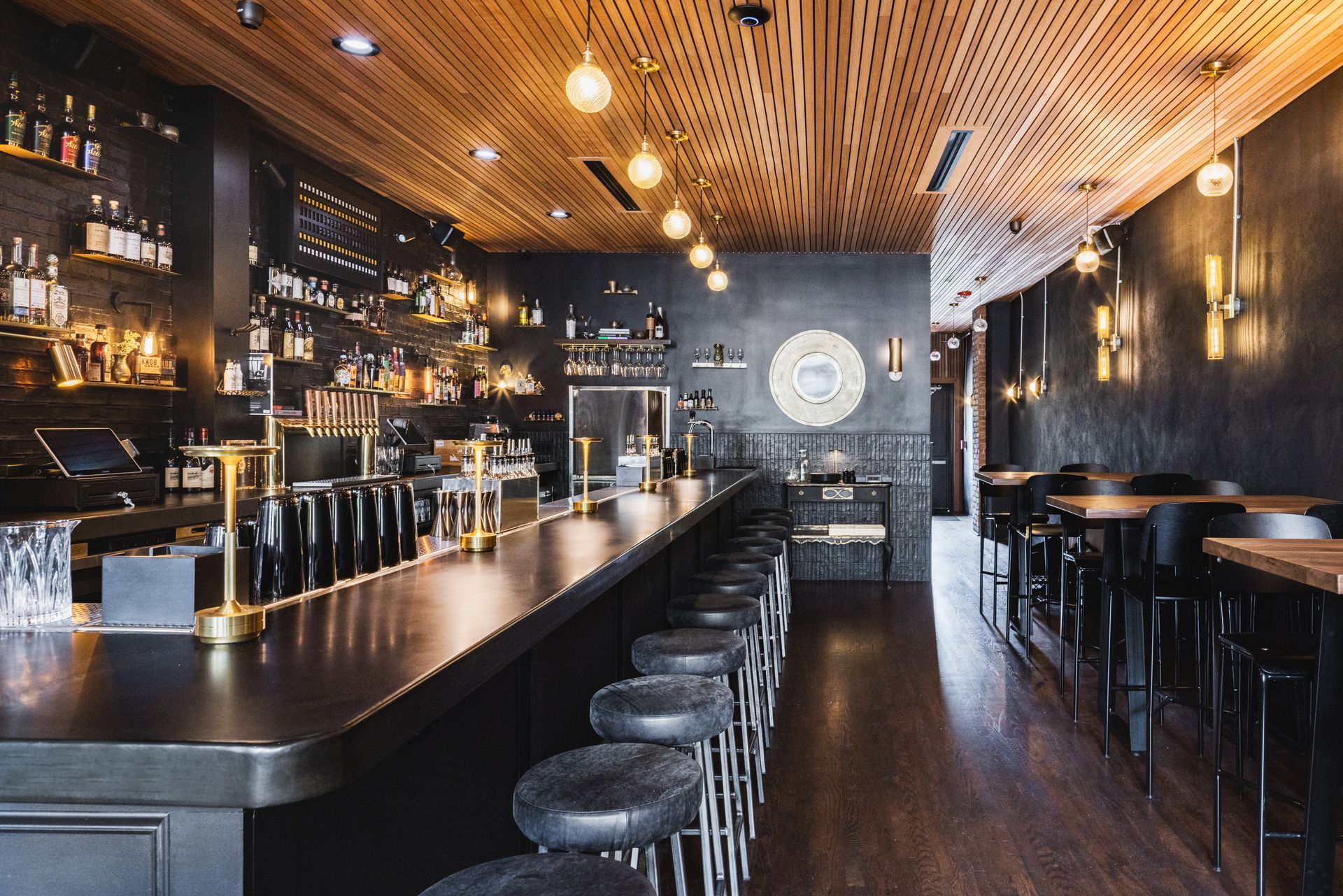The interior of a restaurant with a long bar and stools.