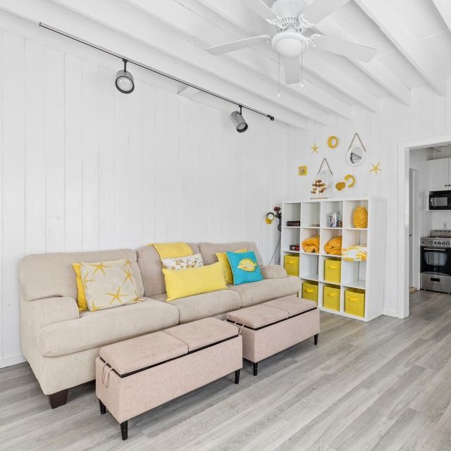 A living room with a couch and ottomans and a ceiling fan