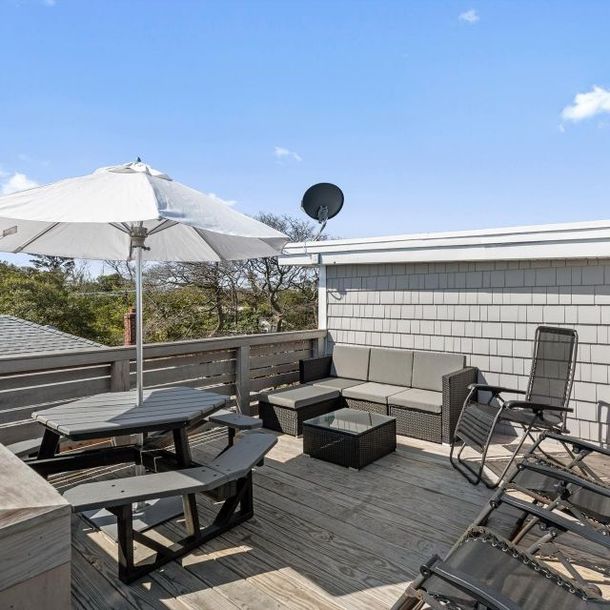 A rooftop deck with a table and chairs under an umbrella