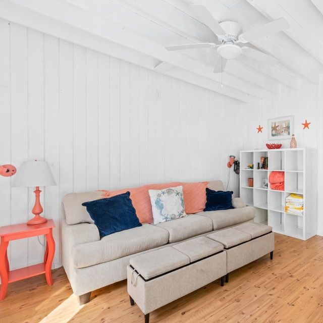 A living room with a couch and ottomans and a ceiling fan