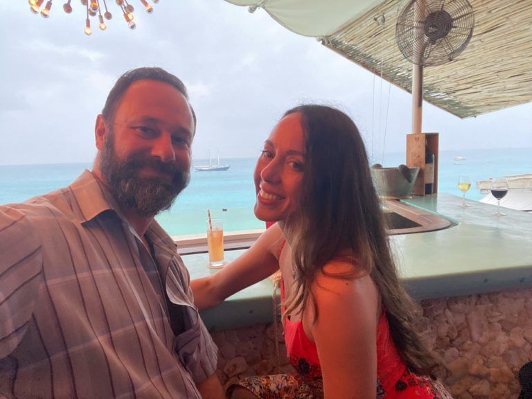 A man and a woman are posing for a picture at a beach bar