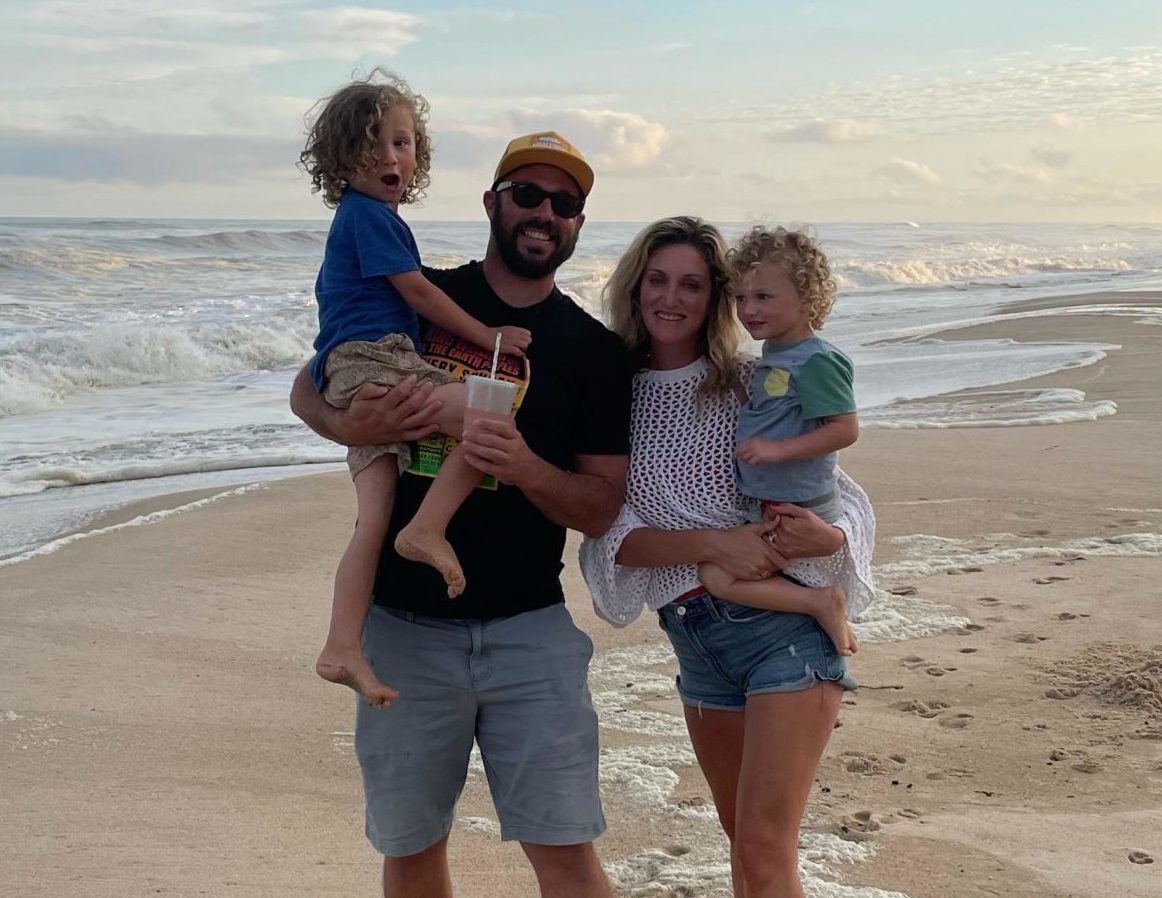 A family is posing for a picture on the beach.