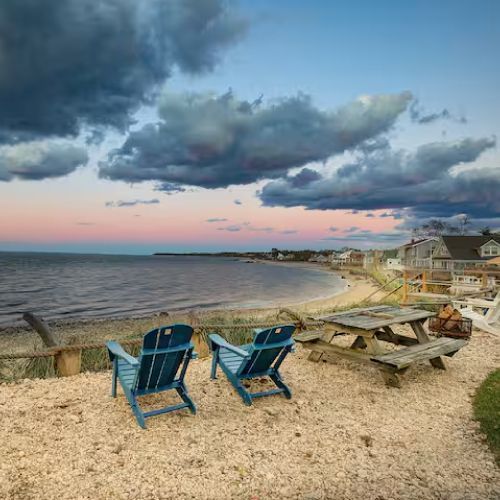 There are two chairs and a picnic table on the beach.