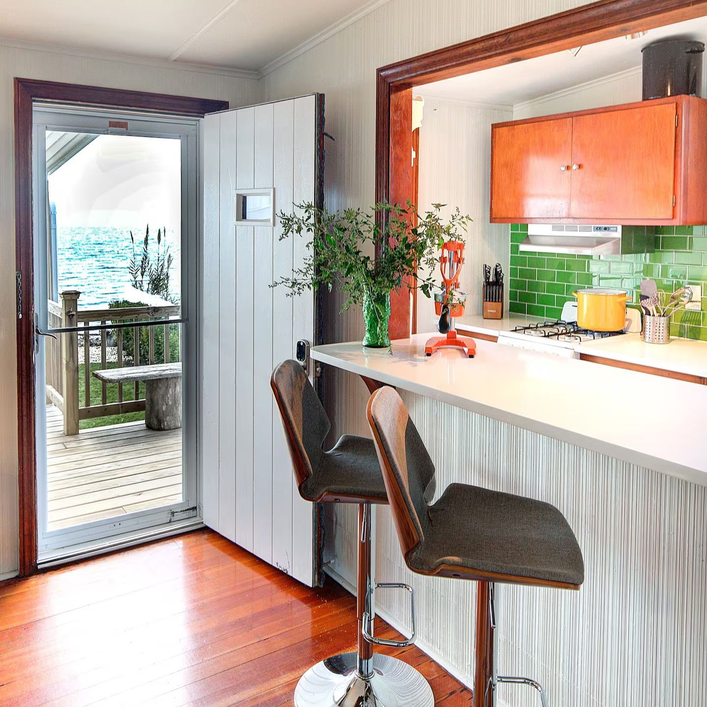 A kitchen with a bar and chairs and a view of the ocean