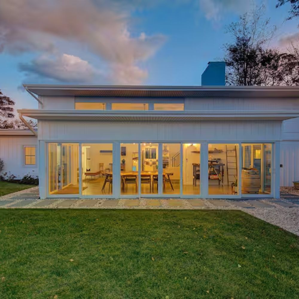 A white house with a lot of windows and a large lawn in front of it.