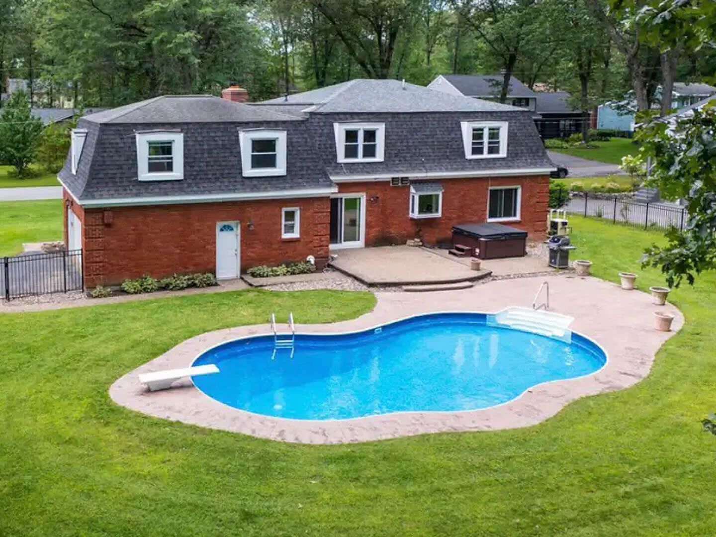A large brick house with a large swimming pool in front of it.
