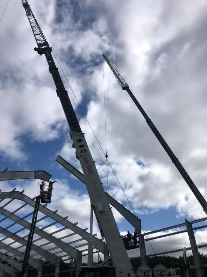 Link-belt cranes are silhouetted against a beautiful cloudy Vermont sky