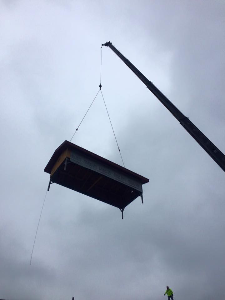 A crane lowers a large structure into place on a construction site