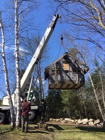 A crane lifts and relocates a shed