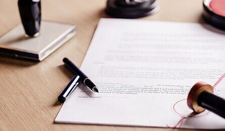 Papers, pens, and stamps scattered on a table - Orlando, Florida - Law Offices of Amber Jade Johnson, PA