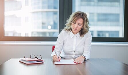 Woman looking stressed and writing on a piece of paper in a bright office - Orlando, Florida - Law Offices of Amber Jade Johnson, PA