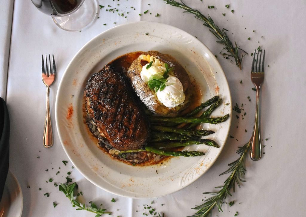 A steak with shrimp and a baked potato on a plate.