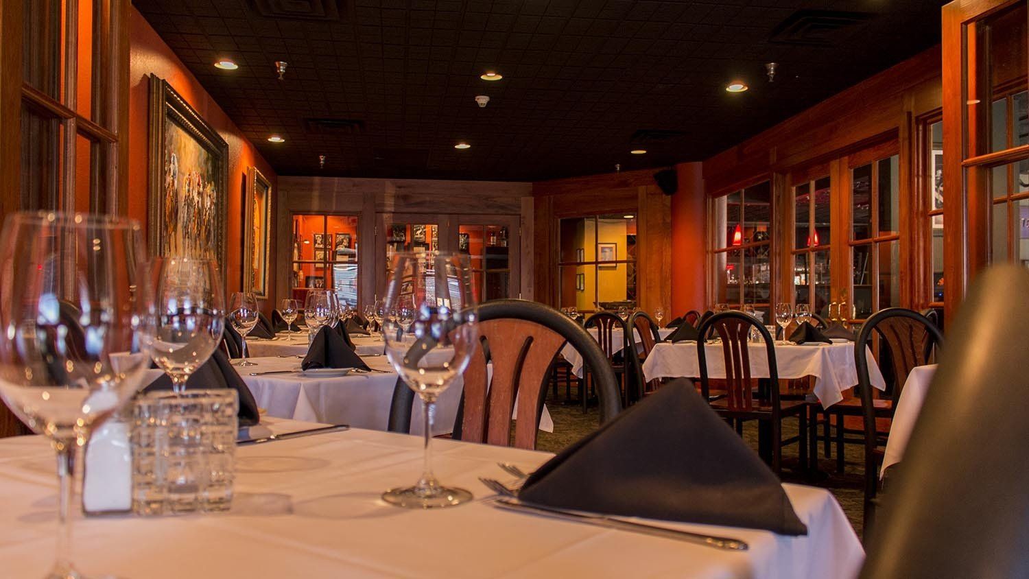 A restaurant filled with tables and chairs and glasses of wine.