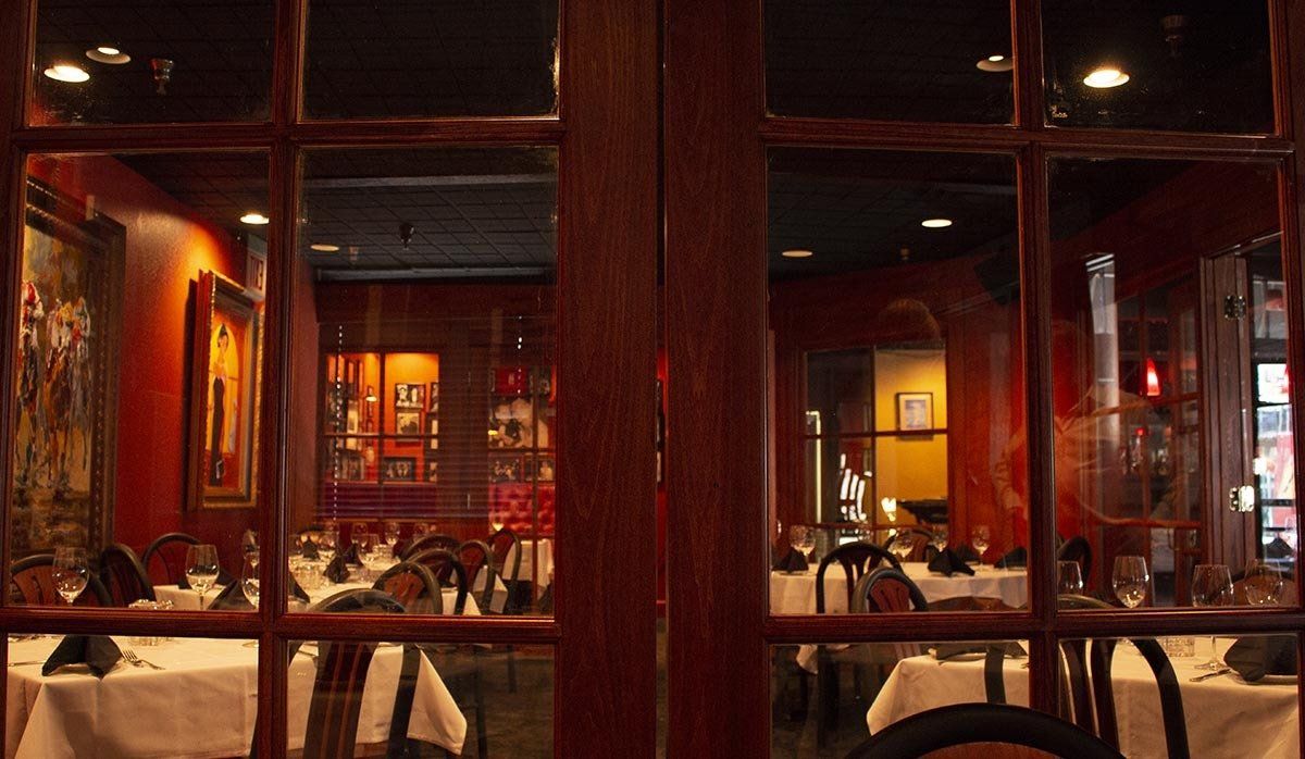 A restaurant with tables and chairs behind a glass door