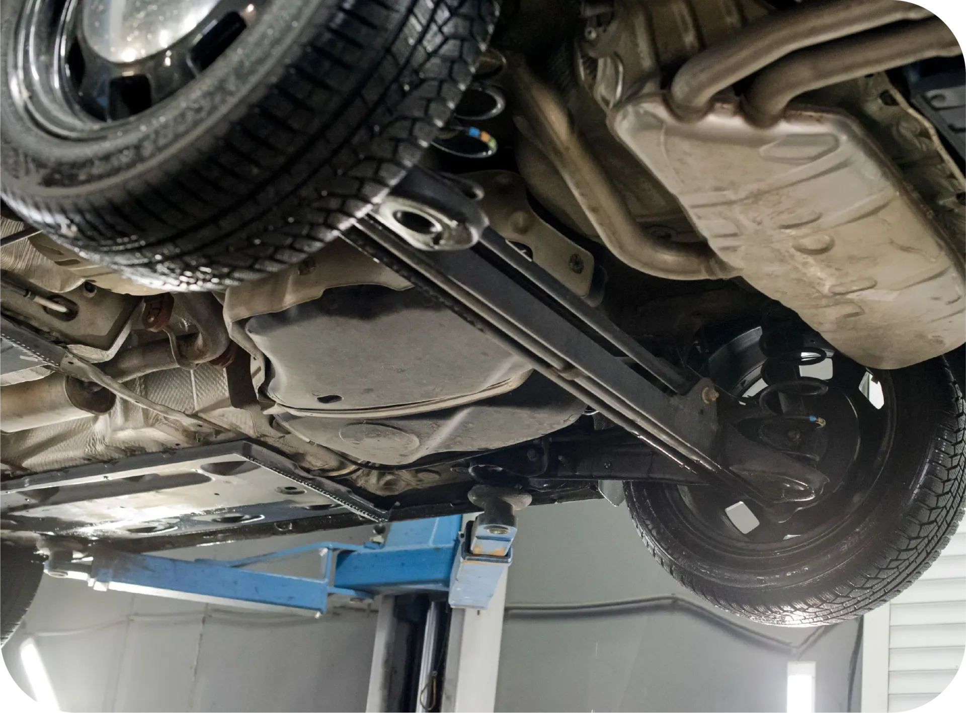 The underside of a car on a lift in a garage.